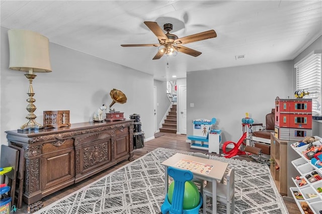 game room with baseboards, a ceiling fan, wood finished floors, and visible vents