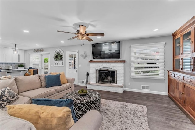 living room with a ceiling fan, visible vents, a fireplace, dark wood finished floors, and recessed lighting