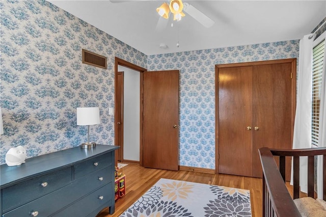 bedroom featuring visible vents, a closet, baseboards, wallpapered walls, and light wood-type flooring