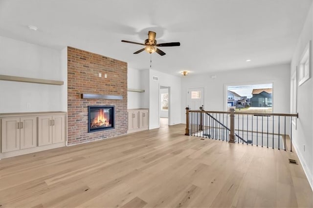 8804 NE 81st Ter, Kansas City, MO 64158 - unfurnished living room with a ceiling fan, a fireplace, light wood-style flooring, baseboards, and visible vents