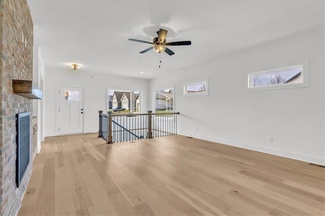 8804 NE 81st Ter, Kansas City, MO 64158 - unfurnished living room featuring baseboards, a fireplace, light wood-style floors, and a ceiling fan