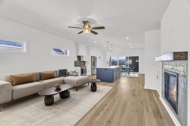 8137 N Farley Ave, Kansas City, MO 64158 - living room featuring recessed lighting, a glass covered fireplace, ceiling fan, and light wood-type flooring