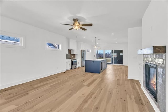 8137 N Farley Ave, Kansas City, MO 64158 - unfurnished living room with a sink, a ceiling fan, light wood finished floors, a fireplace, and baseboards