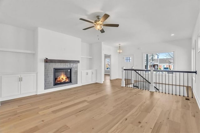 8137 N Farley Ave, Kansas City, MO 64158 - unfurnished living room with a glass covered fireplace, light wood-style floors, built in shelves, and ceiling fan