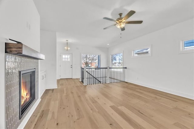 8137 N Farley Ave, Kansas City, MO 64158 - unfurnished living room with a glass covered fireplace, baseboards, light wood finished floors, and ceiling fan