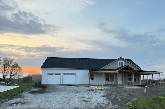farmhouse with covered porch, driveway, and an attached garage