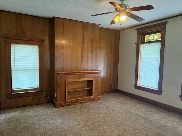 1014 S 12th St, Saint Joseph, MO 64503 - unfurnished living room with carpet flooring, wooden walls, plenty of natural light, ceiling fan, and baseboards