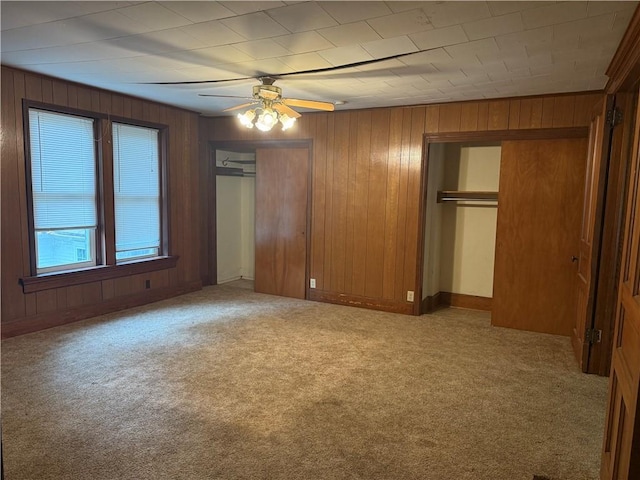 1014 S 12th St, Saint Joseph, MO 64503 - unfurnished bedroom with multiple closets, carpet, wooden walls, a ceiling fan, and baseboards