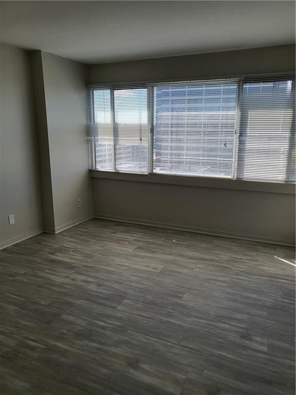 empty room featuring baseboards and dark wood finished floors