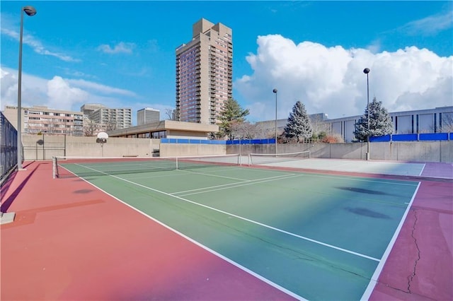 view of tennis court featuring community basketball court and fence
