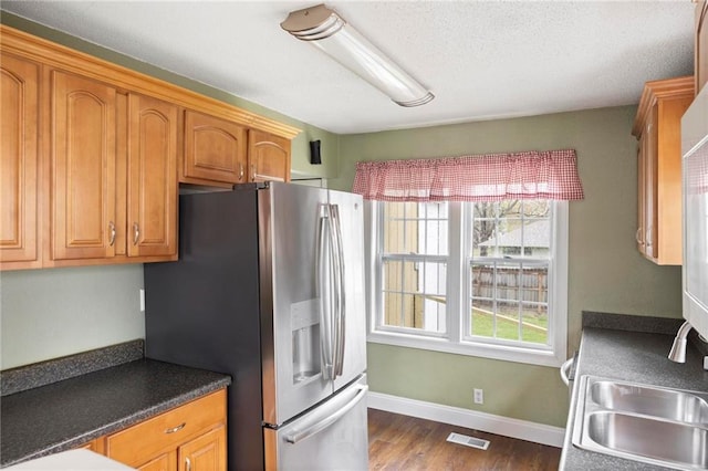 508 S 7th St, Louisburg, KS 66053 - kitchen featuring stainless steel fridge with ice dispenser, dark wood finished floors, dark countertops, brown cabinetry, and a sink
