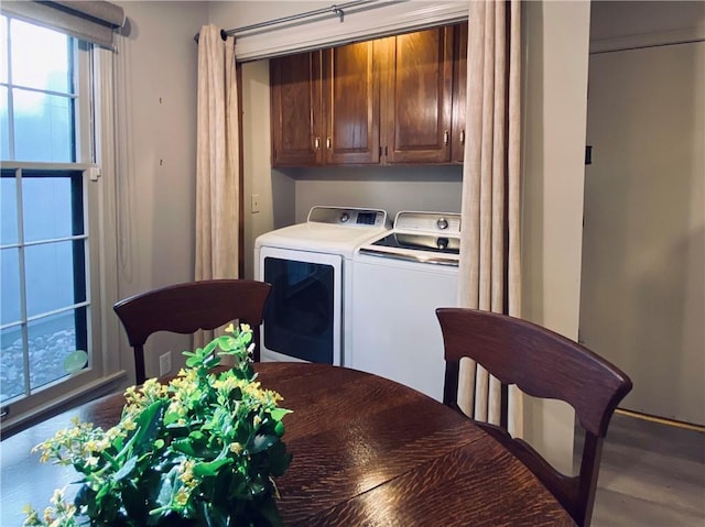 clothes washing area featuring a wealth of natural light, cabinet space, wood finished floors, and washer and clothes dryer