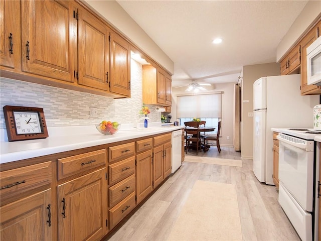 kitchen featuring white appliances, light countertops, light wood-style flooring, a ceiling fan, and backsplash