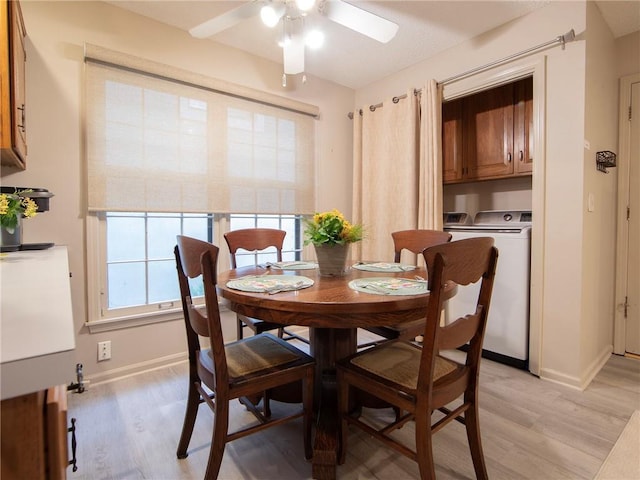 dining area featuring separate washer and dryer, light wood-style flooring, ceiling fan, and baseboards