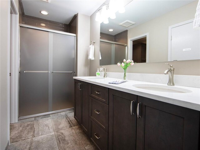 bathroom with double vanity, a sink, a stall shower, and visible vents