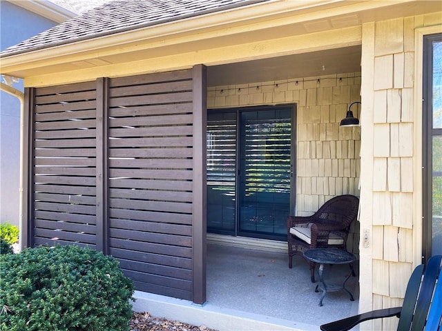 entrance to property featuring roof with shingles