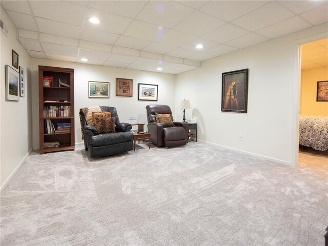 living area featuring baseboards, carpet, built in shelves, and a paneled ceiling