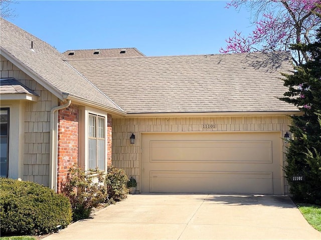 view of front facade featuring brick siding, a garage, driveway, and a shingled roof