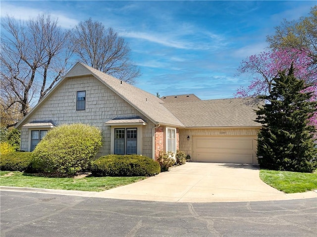 view of front of home with a garage, a shingled roof, and driveway