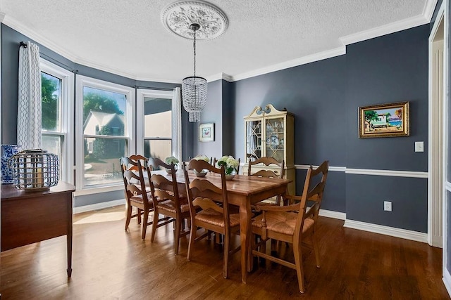 dining room featuring wood finished floors, a textured ceiling, a chandelier, baseboards, and crown molding