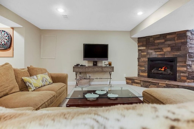 living room featuring a stone fireplace, baseboards, and recessed lighting