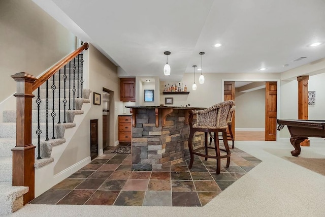 indoor wet bar with baseboards, recessed lighting, stairs, decorative light fixtures, and dark stone finish flooring