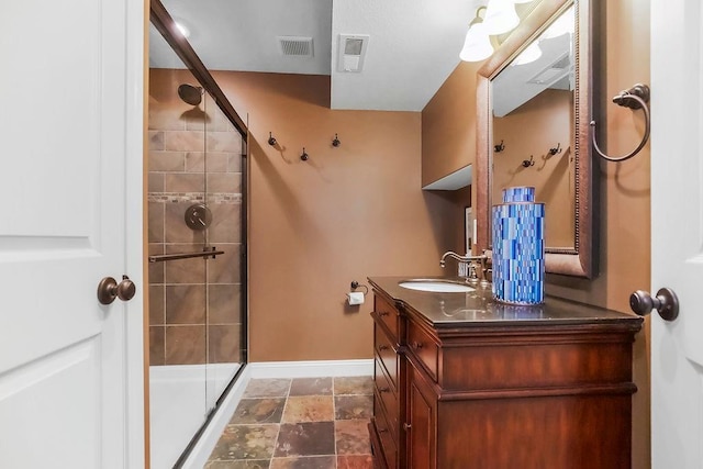 full bathroom featuring a stall shower, baseboards, vanity, and stone finish floors