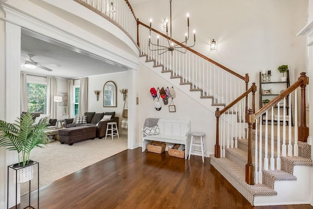 14327 King St, Overland Park, KS 66221 - staircase with wood finished floors, a high ceiling, a chandelier, ceiling fan, and baseboards
