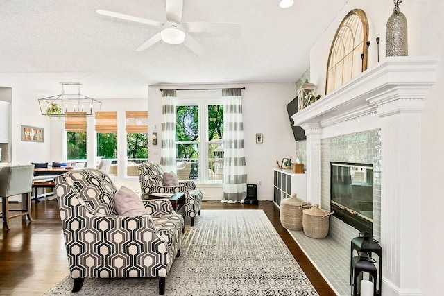 14327 King St, Overland Park, KS 66221 - living area with dark wood-style flooring, ceiling fan, a fireplace with flush hearth, a textured ceiling, and baseboards