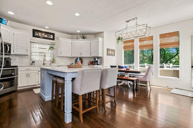14327 King St, Overland Park, KS 66221 - kitchen featuring appliances with stainless steel finishes, white cabinets, light countertops, decorative backsplash, and a textured ceiling