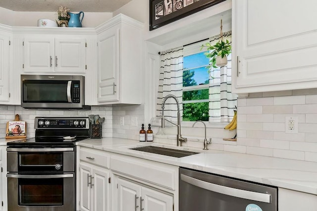 14327 King St, Overland Park, KS 66221 - kitchen featuring stainless steel appliances, a sink, white cabinets, light countertops, and tasteful backsplash