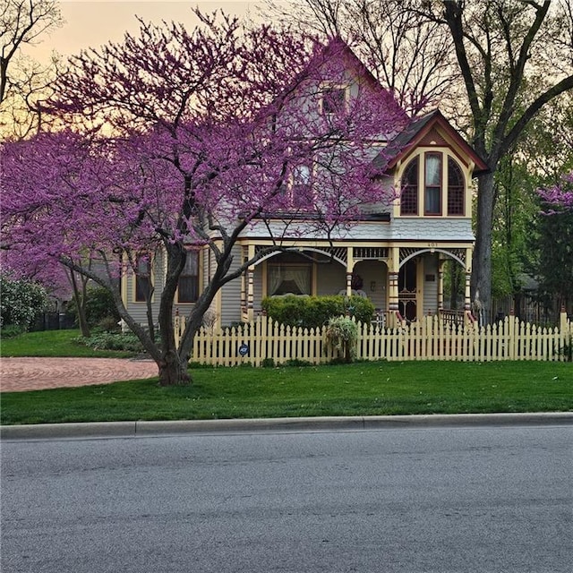 victorian house with a fenced front yard and covered porch