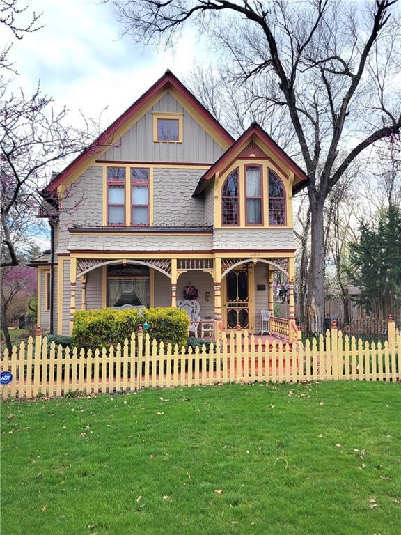 victorian house featuring a front yard, a fenced front yard, covered porch, and board and batten siding