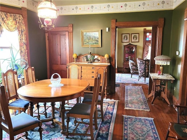 dining space with a notable chandelier, baseboards, and wood finished floors
