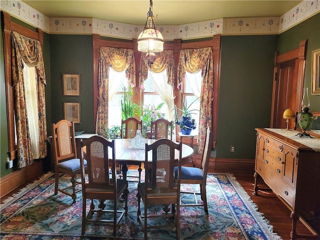 dining space with a chandelier, baseboards, wallpapered walls, and wood finished floors