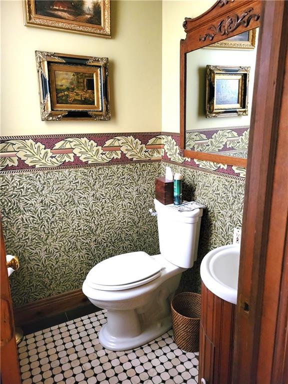 half bath featuring tile patterned floors, a wainscoted wall, toilet, and vanity