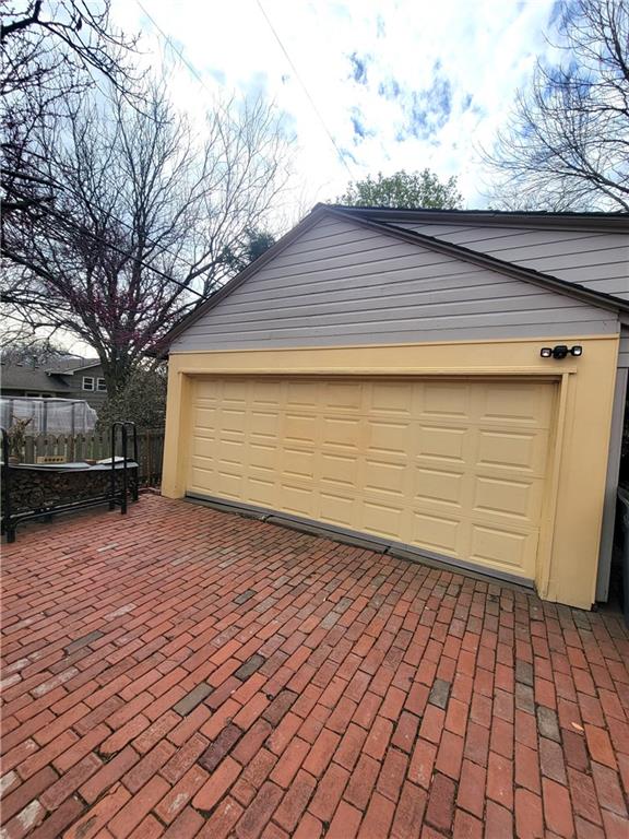 garage featuring fence and decorative driveway