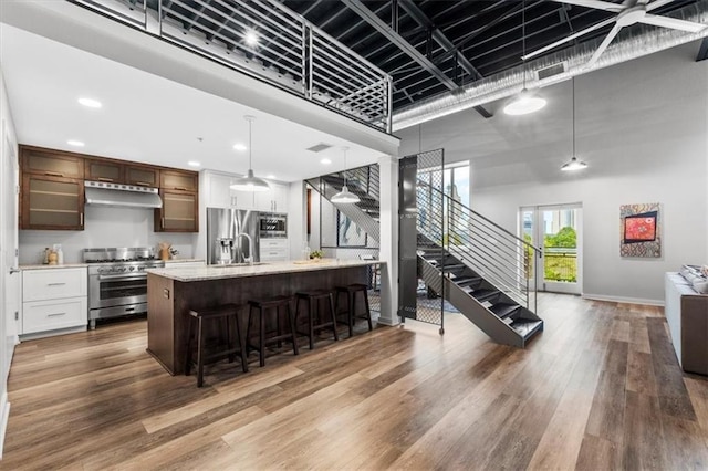 kitchen featuring a breakfast bar area, light wood-style flooring, stainless steel appliances, open floor plan, and under cabinet range hood