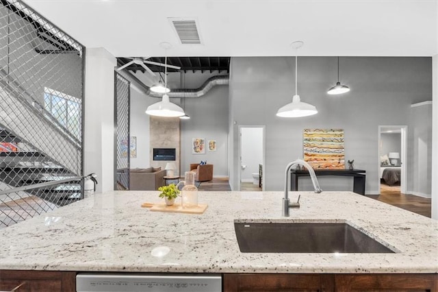 kitchen with light stone countertops, visible vents, a sink, and dishwasher