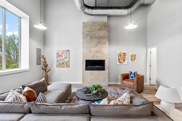 living area featuring plenty of natural light, wood finished floors, a high ceiling, and a tile fireplace