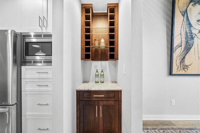 bar with appliances with stainless steel finishes, baseboards, and wood finished floors