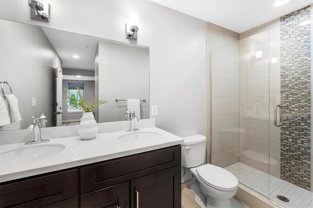 full bath featuring double vanity, a sink, toilet, and a shower stall