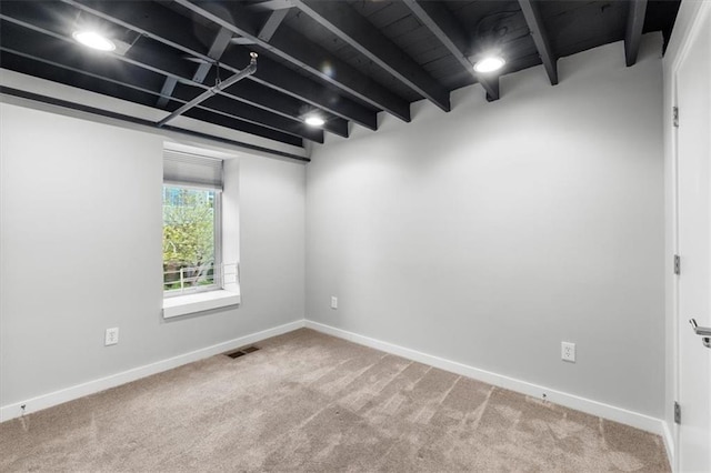 carpeted empty room with baseboards, beamed ceiling, and visible vents