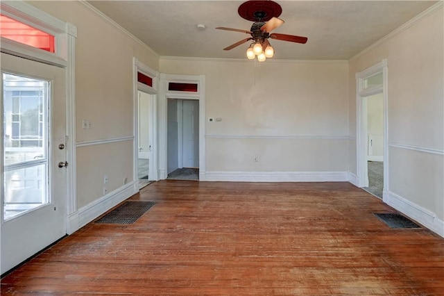empty room featuring a ceiling fan, wood finished floors, ornamental molding, and visible vents