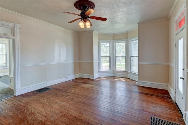 spare room featuring hardwood / wood-style floors, a ceiling fan, crown molding, and visible vents