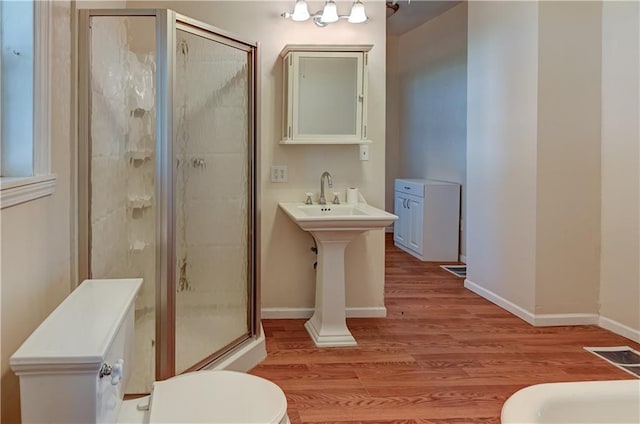 bathroom featuring toilet, a shower stall, wood finished floors, baseboards, and visible vents