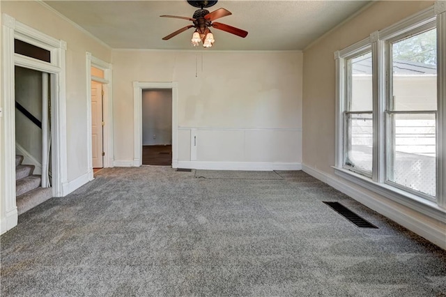 spare room with crown molding, stairway, visible vents, ceiling fan, and carpet