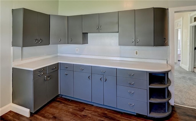 kitchen with light countertops, open shelves, dark wood-style floors, gray cabinets, and dark colored carpet
