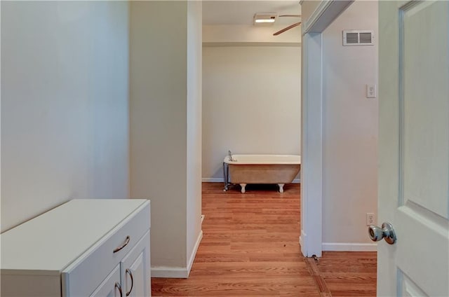 hallway with light wood-style flooring, baseboards, and visible vents