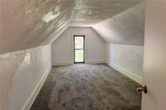 bonus room featuring carpet flooring, a textured ceiling, baseboards, lofted ceiling, and a textured wall